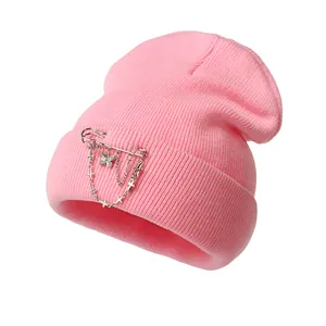 Detailed view of pink knitted beanie featuring silver butterfly and cross chain accessories