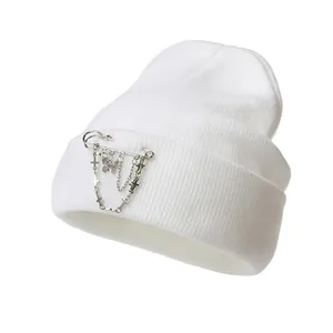 Detail of white ribbed beanie with silver chain butterfly and cross charm accessories