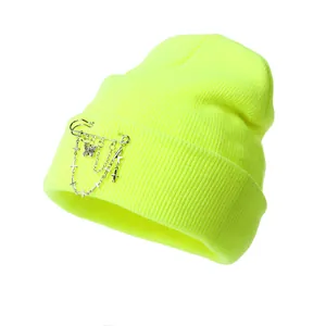 Neon green knit beanie with punk metal chain, butterfly and cross charms on white background