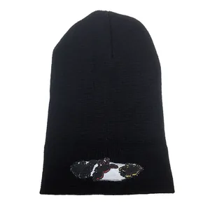 Close-up of tight knit texture and colorful dinosaur embroidery on a black beanie hat