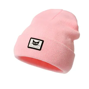 Dettaglio del berretto in maglia rosa chiaro con toppa a gatto nero e trama a coste