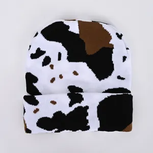 Knit beanie with cow print pattern in white black and brown with cuffed design