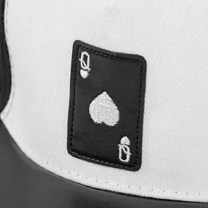 Close-up of black leather patch with Queen of Spades embroidery on a white hip hop cap