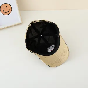 Détail de la casquette kaki avec imprimés dinosaures noirs et broderie requin à l'intérieur