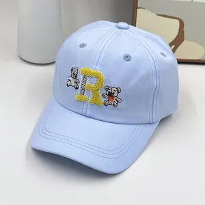 Détail d'une casquette enfant bleu clair avec broderie lettre R et motifs d'oursons
