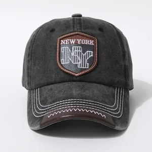 Detail of vintage washed grey baseball cap with brown leather brim and New York embroidery