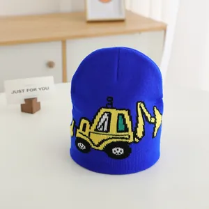 Detail of blue knitted kids beanie featuring a yellow excavator cartoon pattern