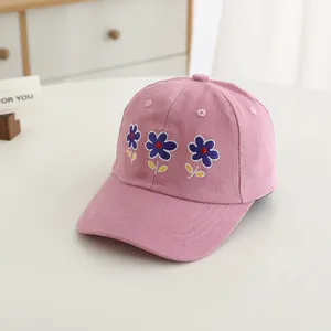 Close-up of pink cotton baseball cap featuring detailed purple flower embroidery