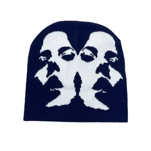 Detailed view of navy blue and white knit beanie featuring an abstract face sketch pattern