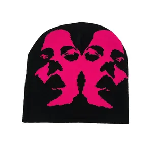 Detailed view of black knitted beanie featuring hot pink face sketch jacquard pattern