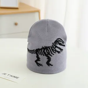 Close-up of grey knit beanie featuring a black dinosaur skeleton pattern on soft fabric