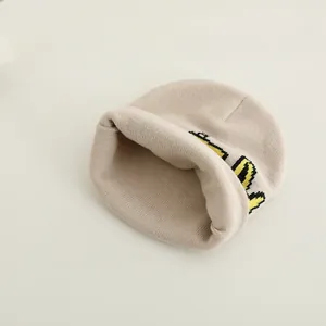 Cozy cream knitted beanie for kids featuring a stylish cartoon excavator pattern design