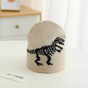 Close-up of beige knitted beanie featuring a detailed black dinosaur skeleton pattern