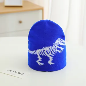Close-up of bright blue knitted beanie featuring white dinosaur skeleton jacquard patterns