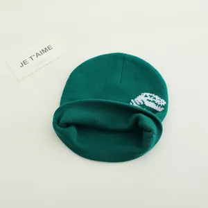 Deep green knitted beanie for kids featuring a white dinosaur jacquard pattern design