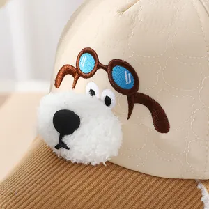 Detail der Kindermütze mit Cartoon-Hunde-Stickerei und beige gesteppter Stoffstruktur