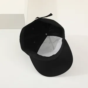 Detailed interior of black cotton baseball cap showing white mesh lining and adjustable strap
