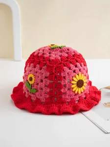 Detail eines rot-rosa gehäkelten Fischerhuts mit Sonnenblumen-Applikationen und Wellenrand