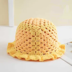 Detail einer gelben handgehäkelten Strickmütze mit gewelltem Rüsselrand-Design