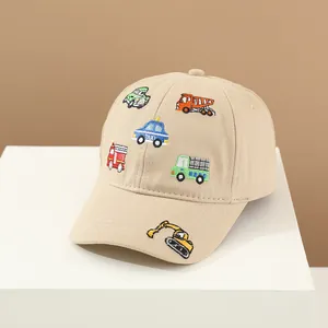 Dettaglio del cappellino beige in cotone con ricami colorati di veicoli a cartoni animati