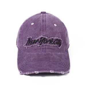 Detailed macro of distressed purple New York City embroidery on washed cotton baseball cap