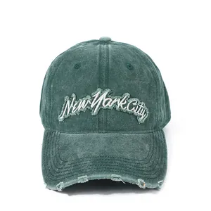 Detailed close-up of distressed brim and New York City embroidery on green cotton cap