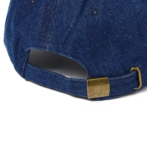 Detail view of denim baseball cap with adjustable metal buckle on dark blue fabric