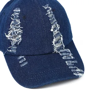 Distressed dark blue denim baseball cap with vintage frayed holes and street style design