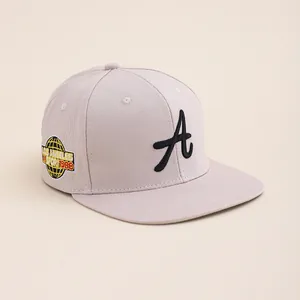 Detail of embroidered A letter on a light beige hip hop baseball cap with side patch