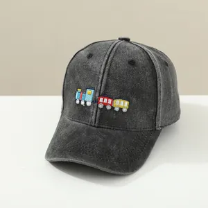 Detail of colorful train embroidery on kids' dark grey washed denim baseball cap