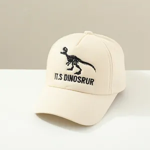 Detailed close-up of beige canvas kid's cap with embroidered dinosaur skeleton design