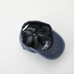 Detail of the blue washed cotton cap showing the internal structure and dinosaur embroidery