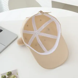 Internal view of beige cap with 3D ear detail and adjustable buckle on white background