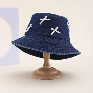 Chapeau bob en denim bleu marine avec nœuds blancs sur un support en bois pour femme