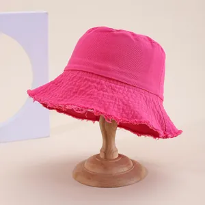 Dettaglio cappello alla pescatora rosa con bordi sfrangiati e trama in tela denim