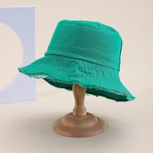 Dettaglio ravvicinato di un cappello pescatore verde con bordi sfrangiati decorativi