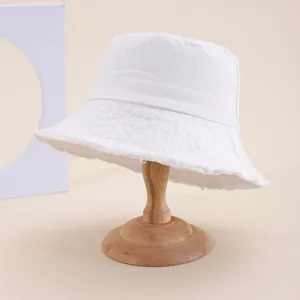 Dettaglio cappello a secchiello in cotone bianco con bordi grezzi su supporto in legno