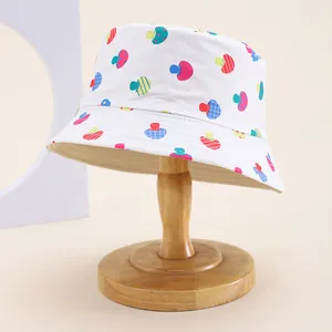Detail of white cotton bucket hat with colorful mushroom print on a wooden stand