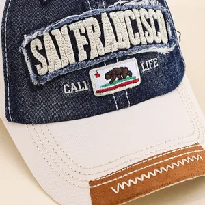 Detailed close-up of embroidered San Francisco patch and California bear on denim baseball cap