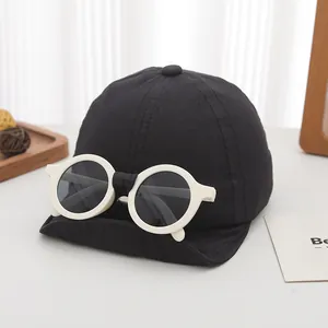 Detalle de gorra de béisbol para niños con gafas integradas sobre fondo minimalista