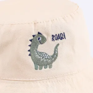 Dettaglio ricamo dinosauro verde e scritta ROAR! su cappello a secchiello beige