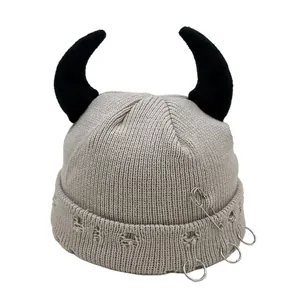 Detail of grey knitted beanie with 3D horns, punk safety pins and metal ring accents