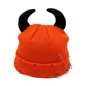 Detailed knit texture of orange devil horn beanie with safety pin and metal rings