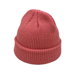 Detailed close-up of coral pink ribbed knit beanie with thick texture and wide fold