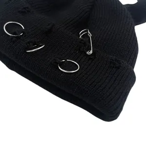 Black knit beanie with devil ears, silver rings and pin decoration in punk style