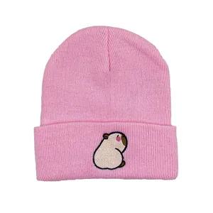 Detail van een roze gebreide muts met een schattig capibara-borduursel op de omslag
