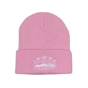 Detail shot of pink knitted beanie with white embroidery showing fabric texture