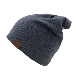 Close-up of dark grey beanie with honeycomb knit texture and leather F&S logo label