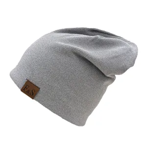 Close-up of light grey waffle knit beanie with a brown leather F&S logo patch