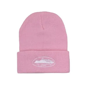 Detail of pink knitted beanie featuring white oval mountain landscape embroidery